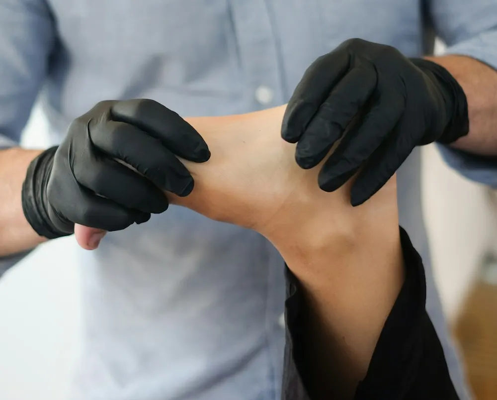 Podólogo con guantes explorando el pie de un paciente